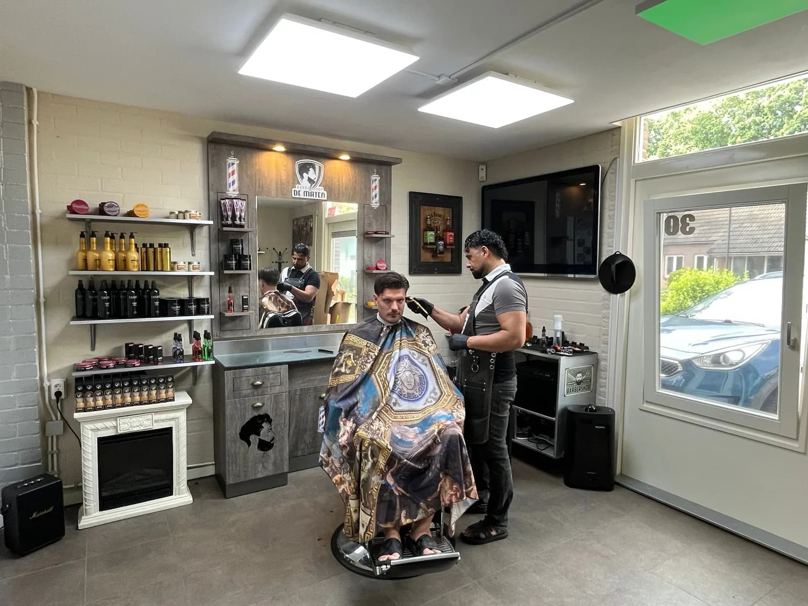 Het interieur van Barbershop De Maten in Apeldoorn terwijl Daniëls een klant knipt