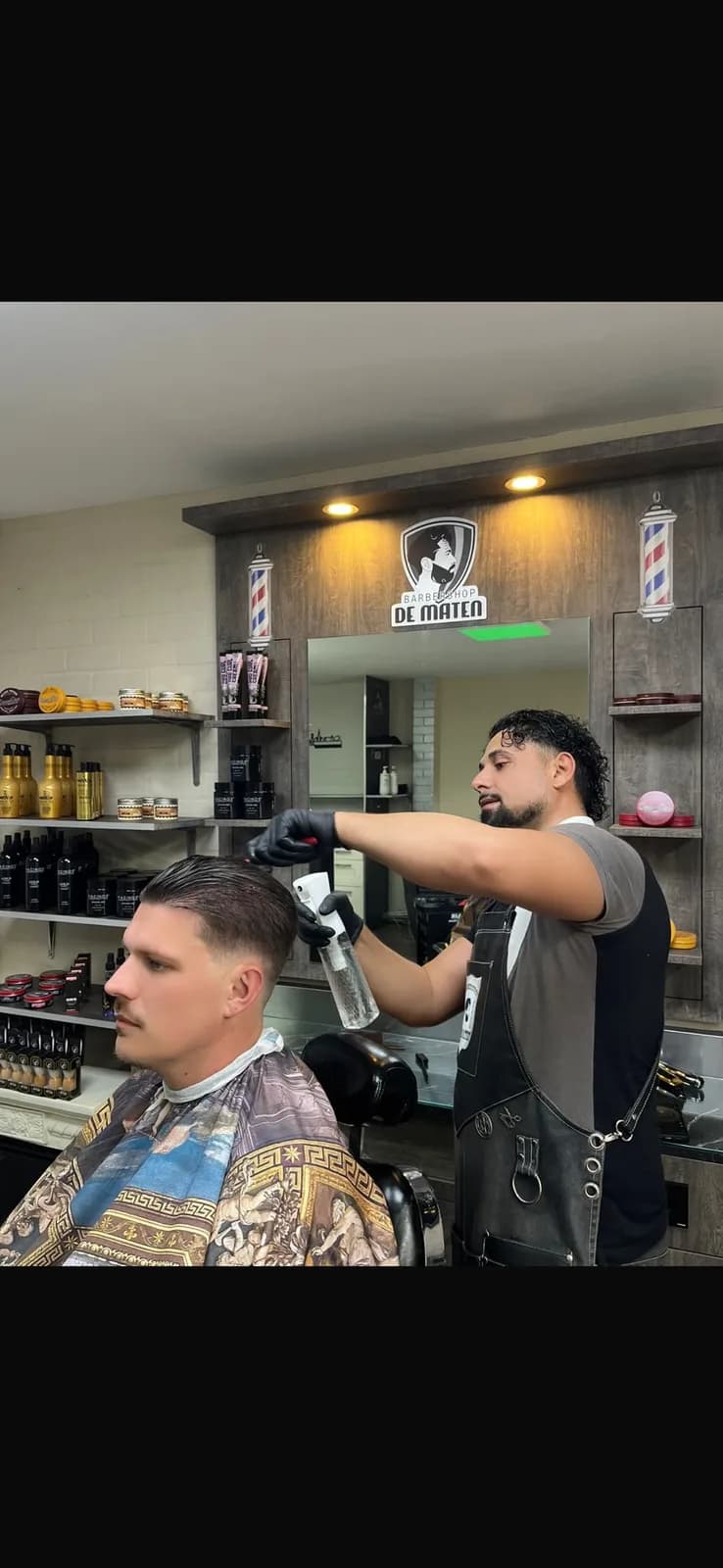 Daniëls stylet het haar van een klant bij Barbershop De Maten in Apeldoorn